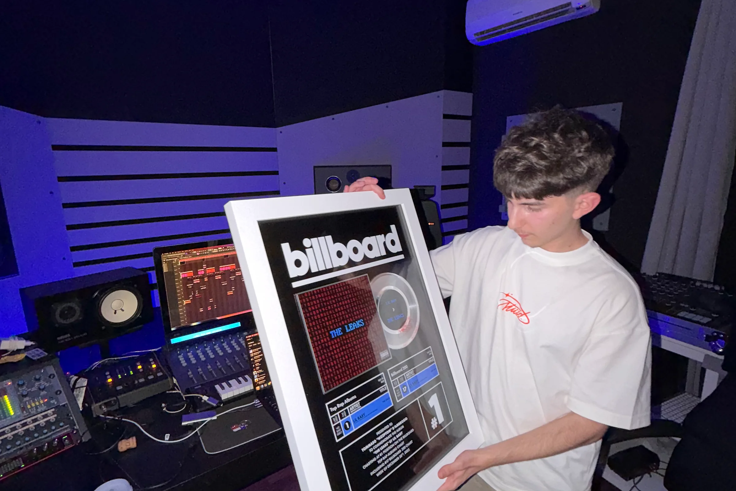 Wzzptom in studio holding the Billboard #1 plaque for Lil Baby's The Leaks